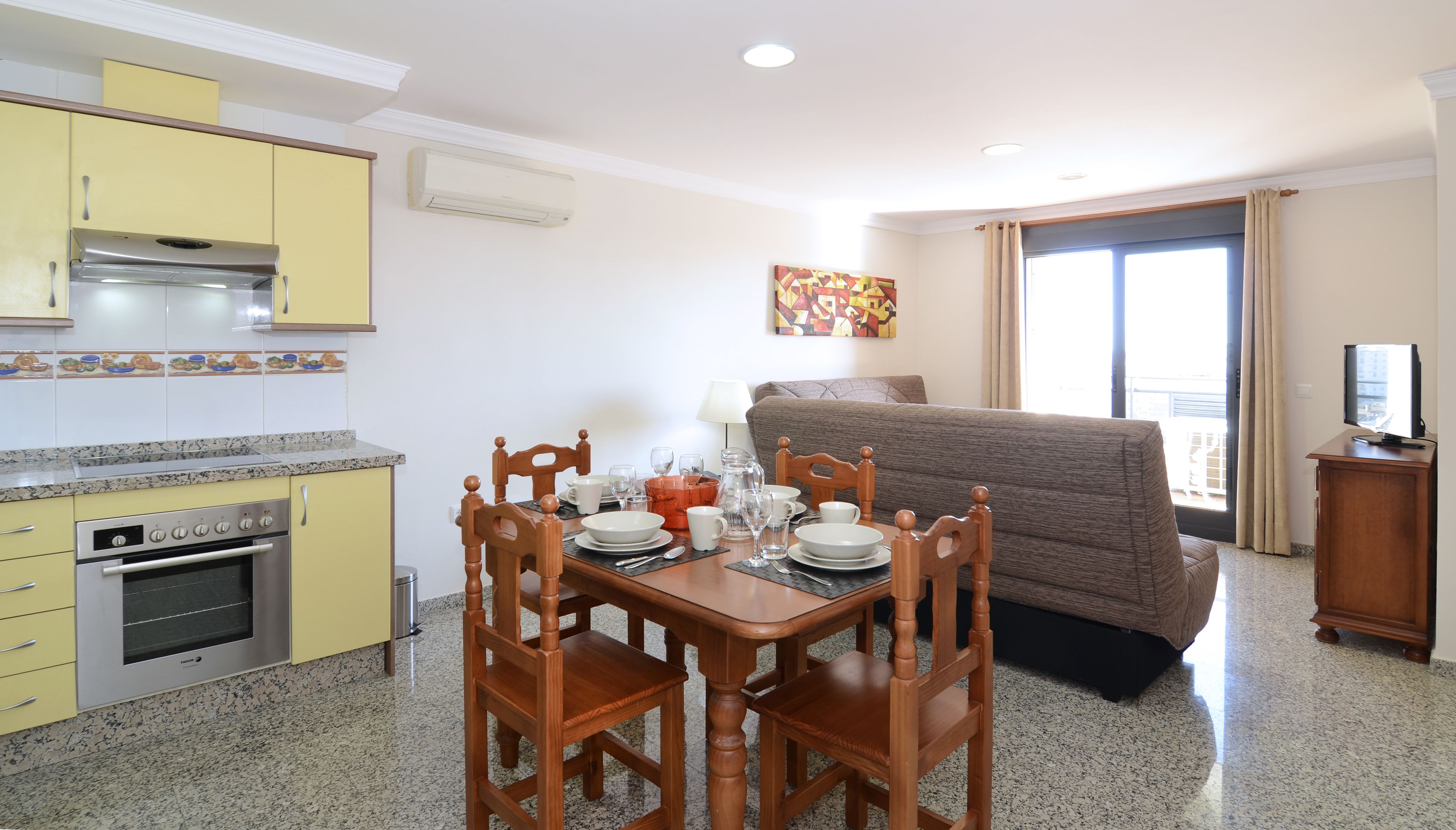 A compact living space with a kitchenette, dining area, and a sofa.