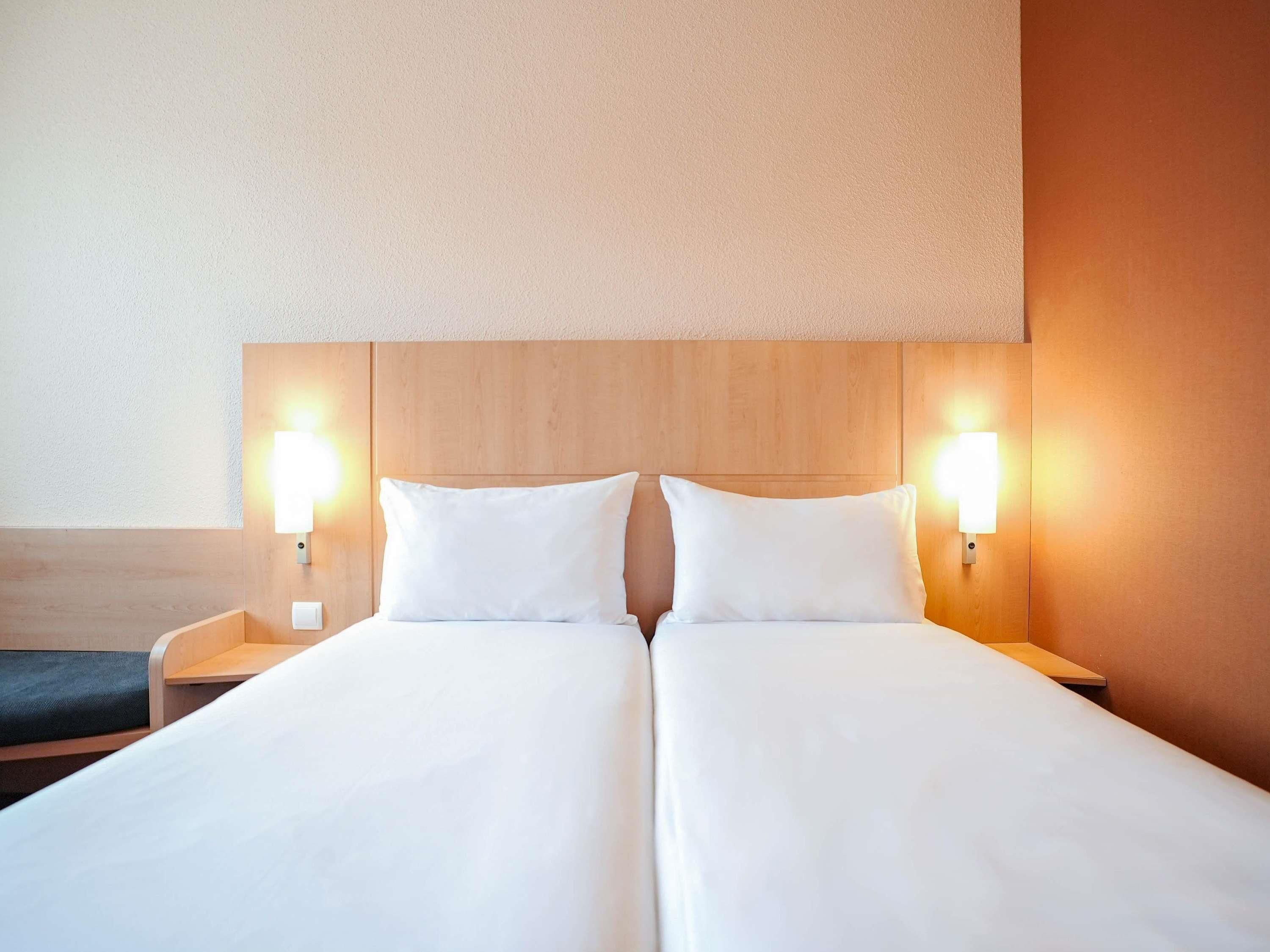 Una cama doble con dos mesitas de noche, cada una con una lámpara de pared.