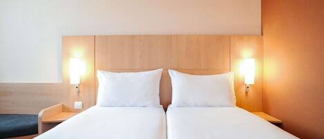 Una cama doble con dos mesitas de noche, cada una con una lámpara de pared.