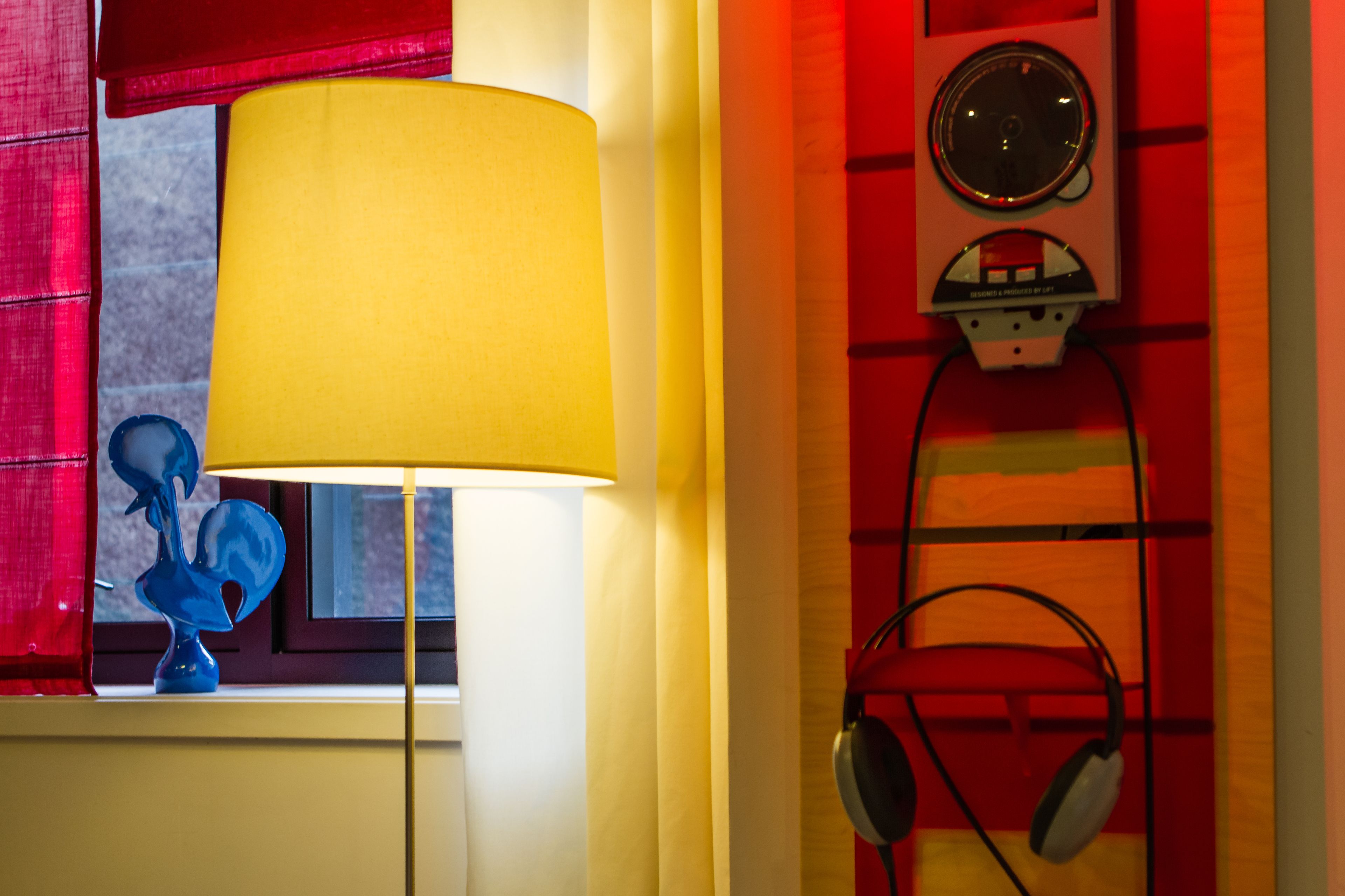 A room with a lamp, a blue sculpture, and headphones on a shelf.