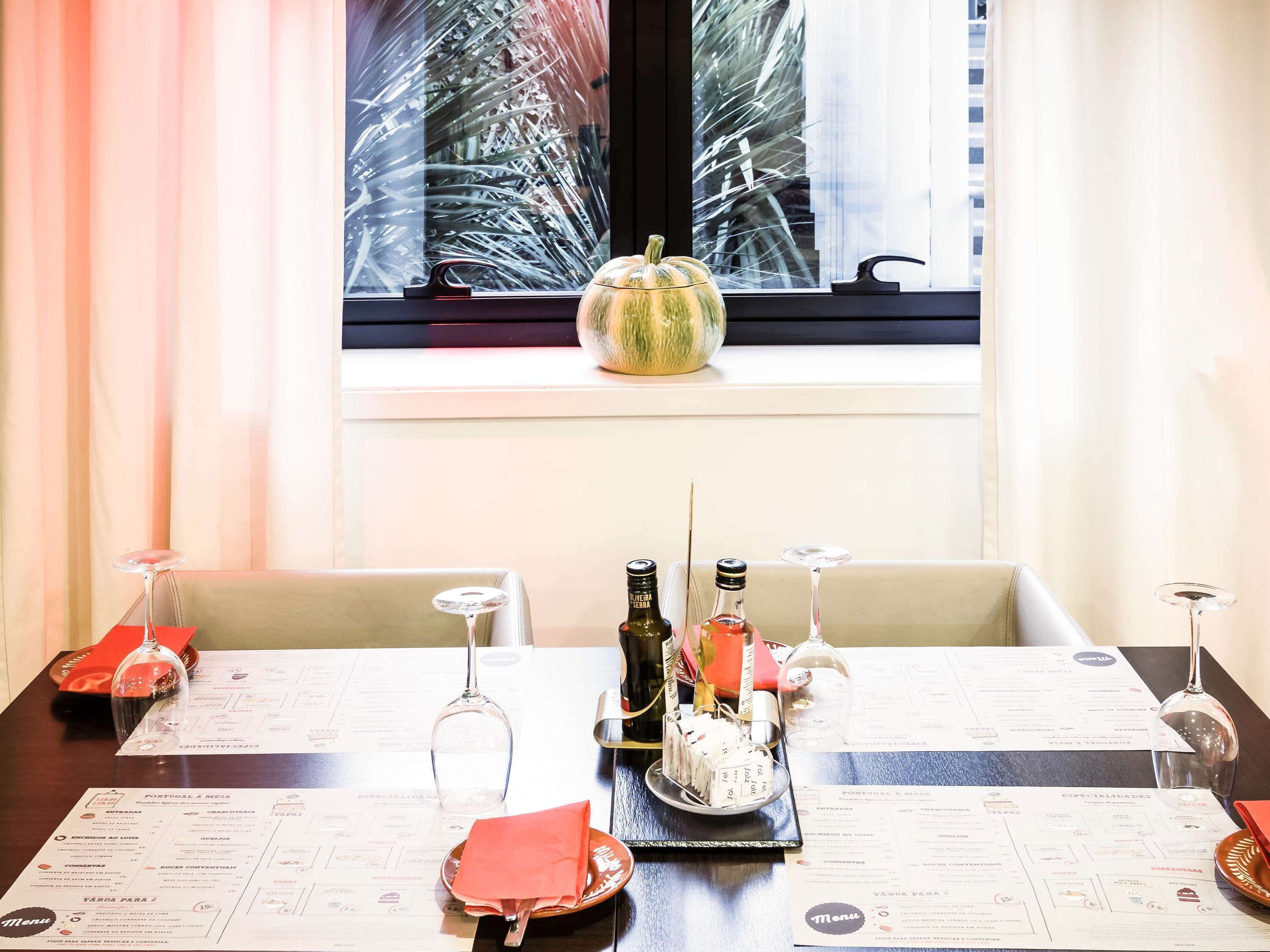 Una mesa de comedor con menús, una decoración de calabaza y una botella de vino.
