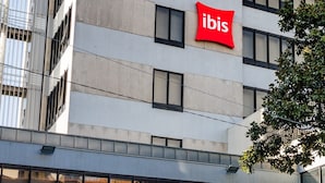 A modern building with a prominent red 'ibis' sign on the facade. - ibis Porto Centro São Bento (Porto)