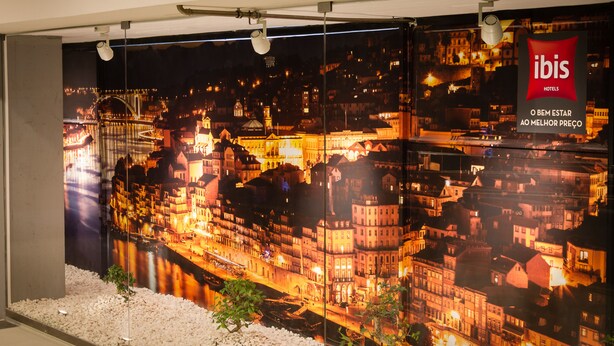 A large poster of a cityscape at night with a prominent ibis hotels logo. - ibis Porto Centro São Bento (Porto)