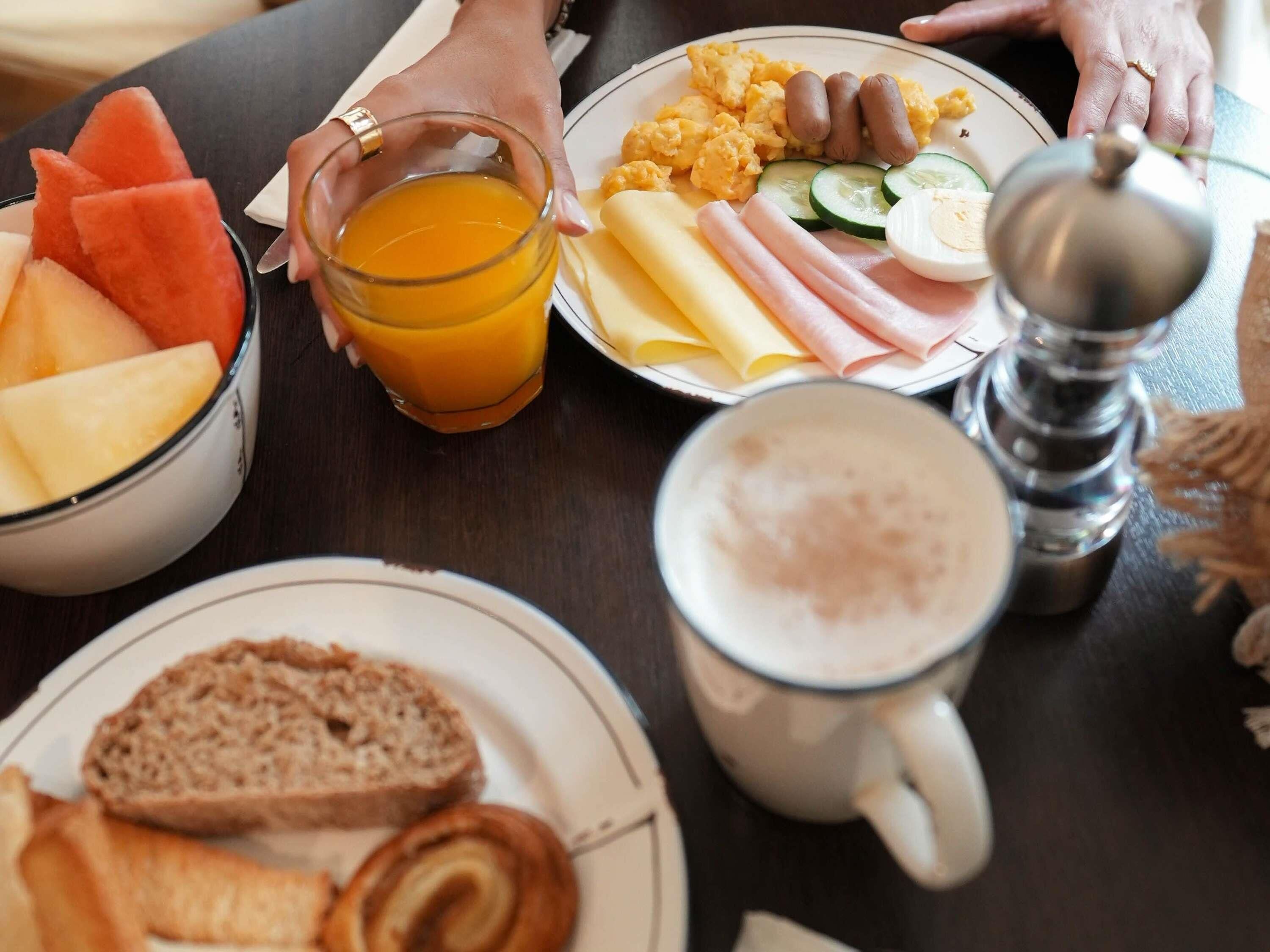 Ein Frühstückstisch mit verschiedenen Speisen, darunter Eier, Schinken, Käse und Obst.