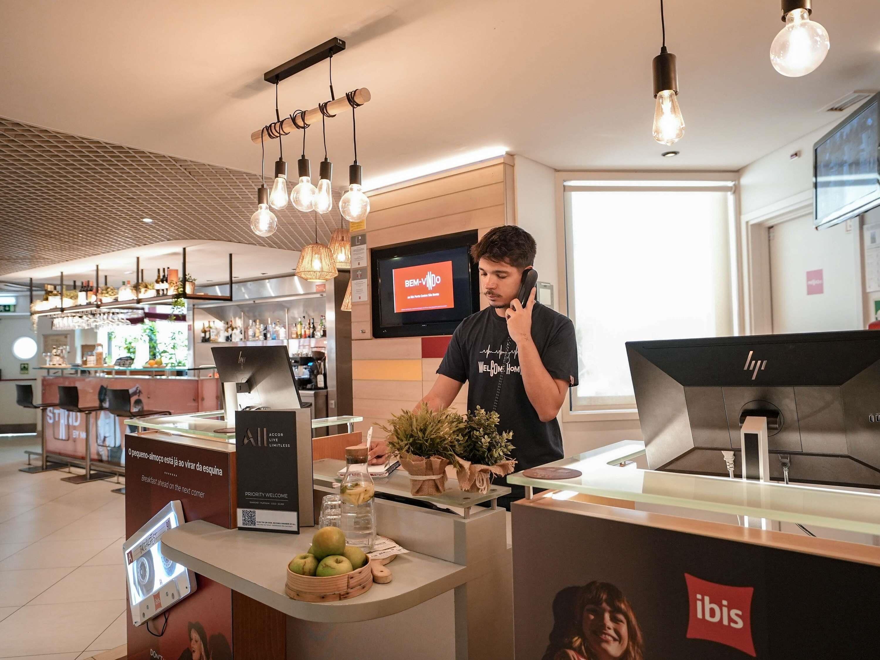 Een modern interieur met een receptiebalie, een digitaal scherm dat een welkomstboodschap toont, en een bar in de achtergrond.