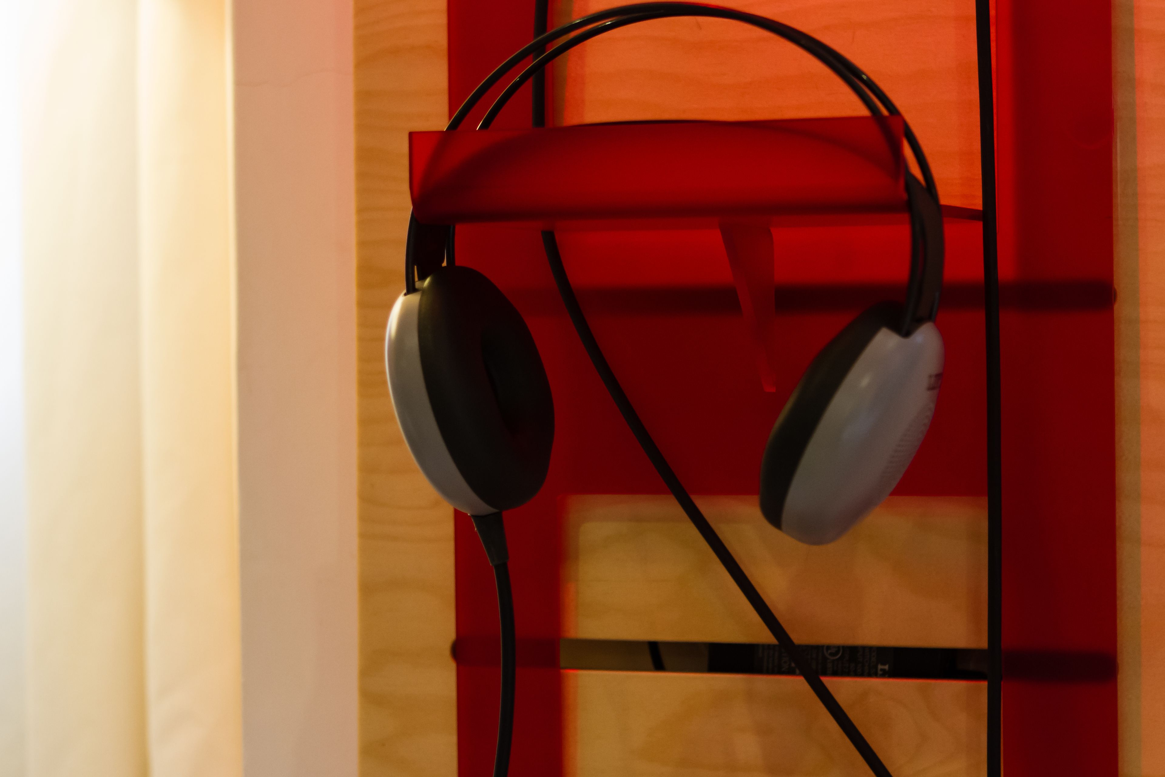 A pair of headphones hanging on a black metal stand.