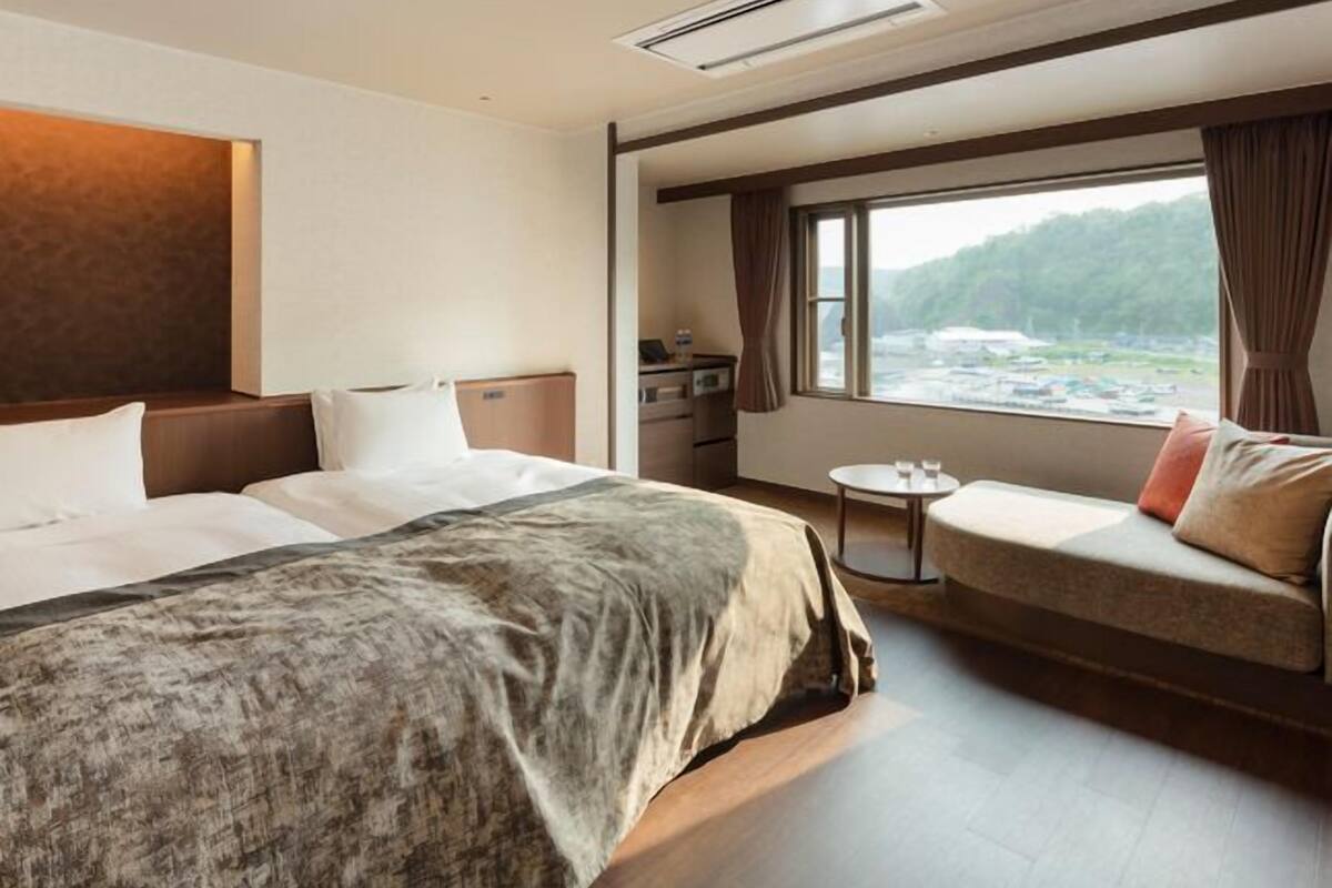 Une chambre d’hôtel avec un grand lit, un canapé, une petite table et une fenêtre donnant sur l’extérieur.