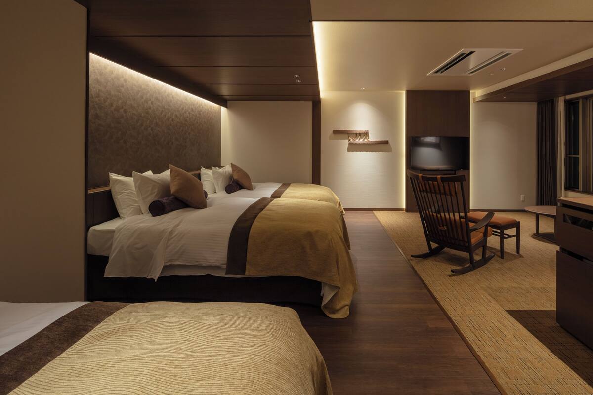 Une chambre d’hôtel avec deux lits, une télévision, un bureau et une chaise.