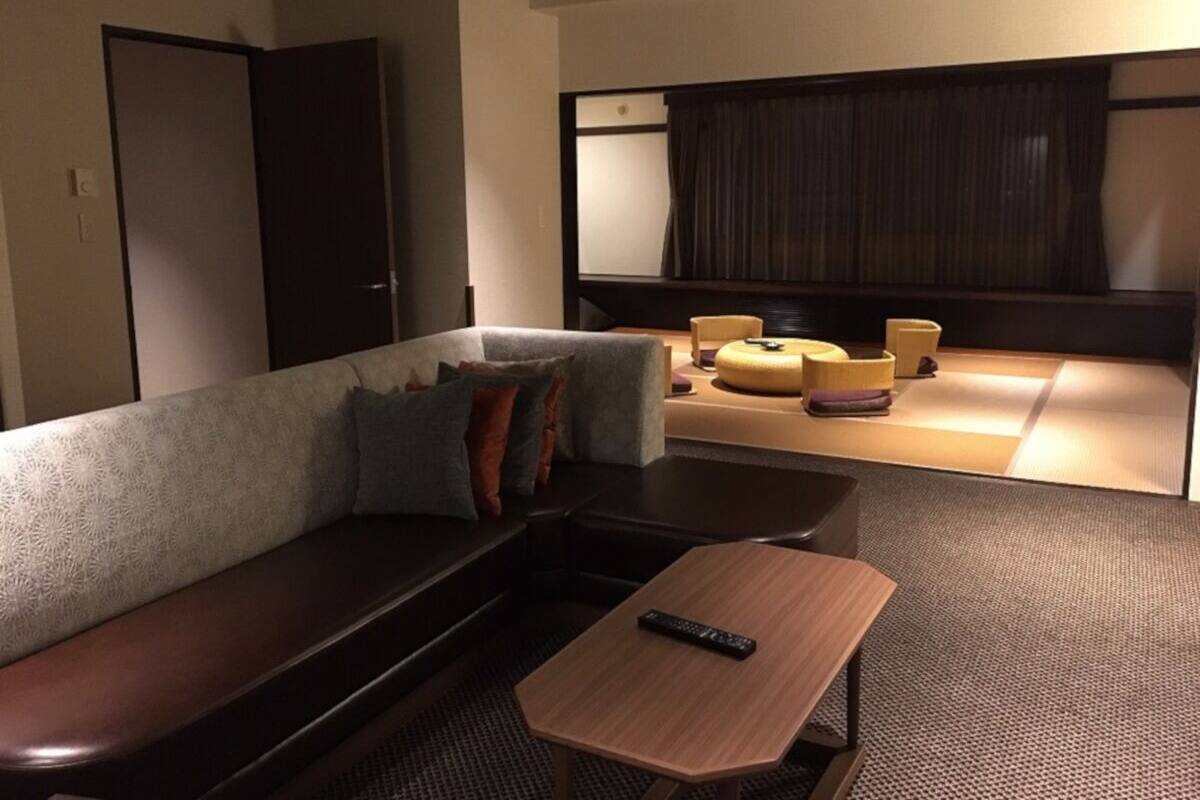 Une chambre d’hôtel avec un canapé, une petite table et une télécommande posée sur la table.