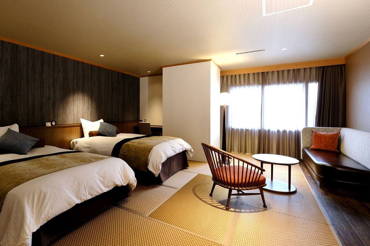 Une chambre d’hôtel avec deux lits, un canapé, une chaise et une petite table.