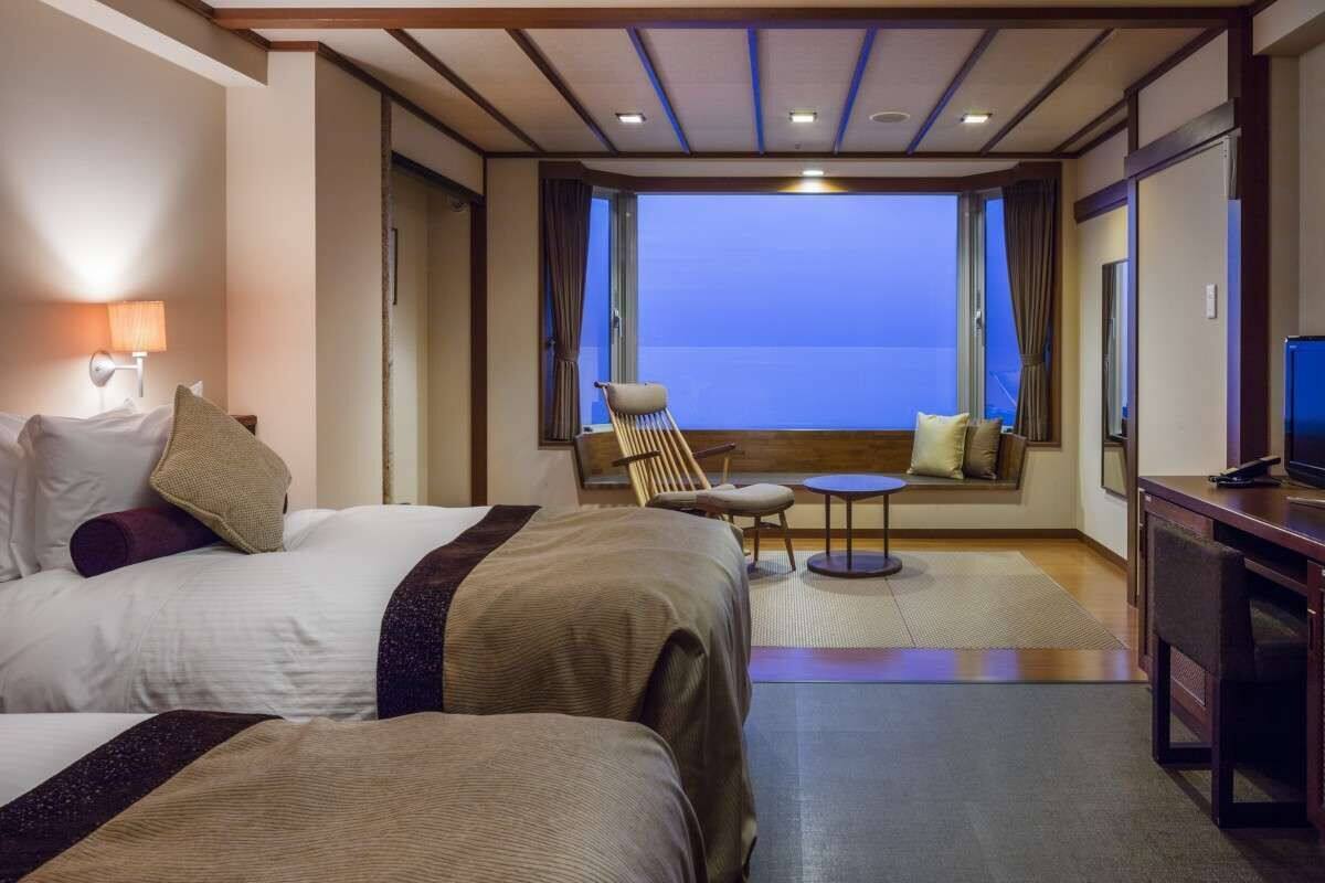 Une chambre d’hôtel avec deux lits, une petite table, une chaise et un téléviseur.