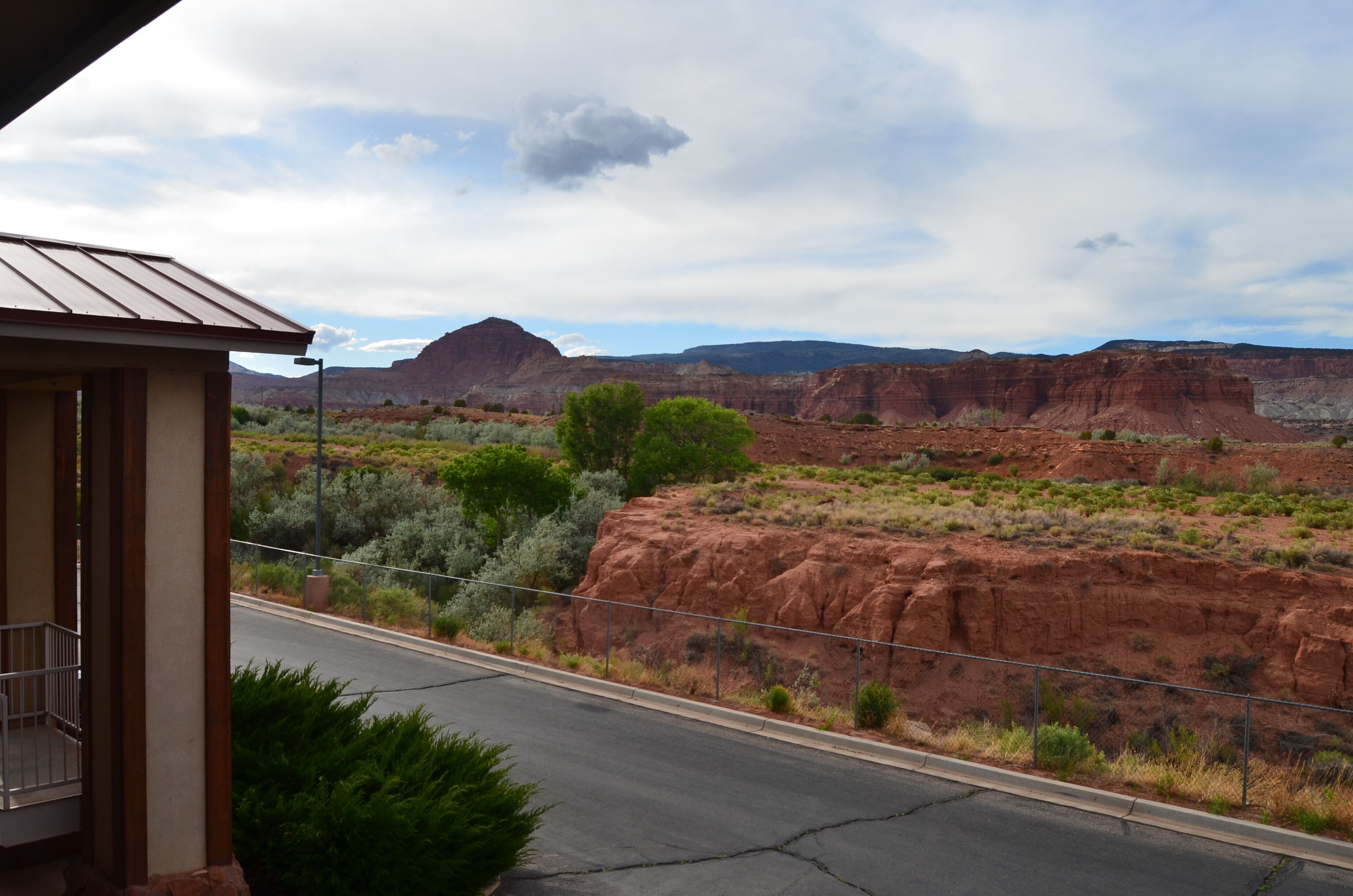 A building with a balcony overlooking a road and a desert landscape with red rock formations.