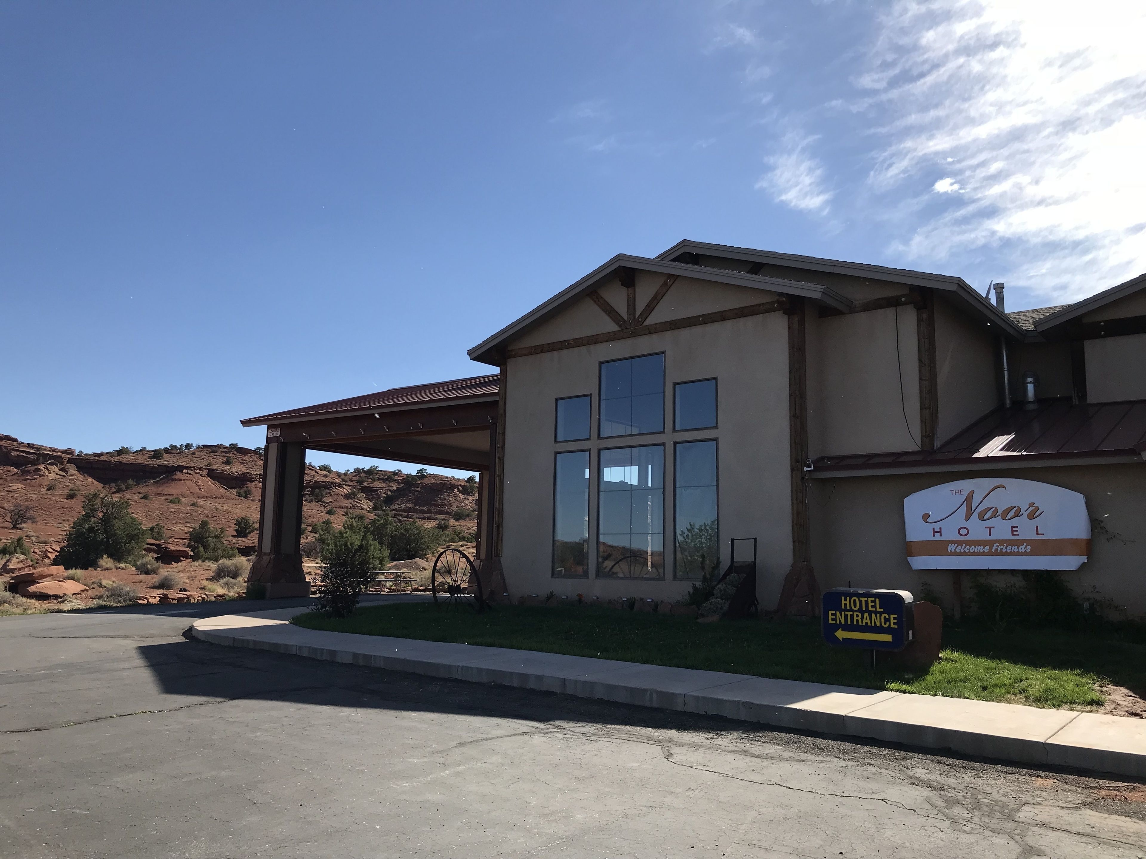 The Noor Hotel with a covered entrance, large windows, and a sign welcoming guests.