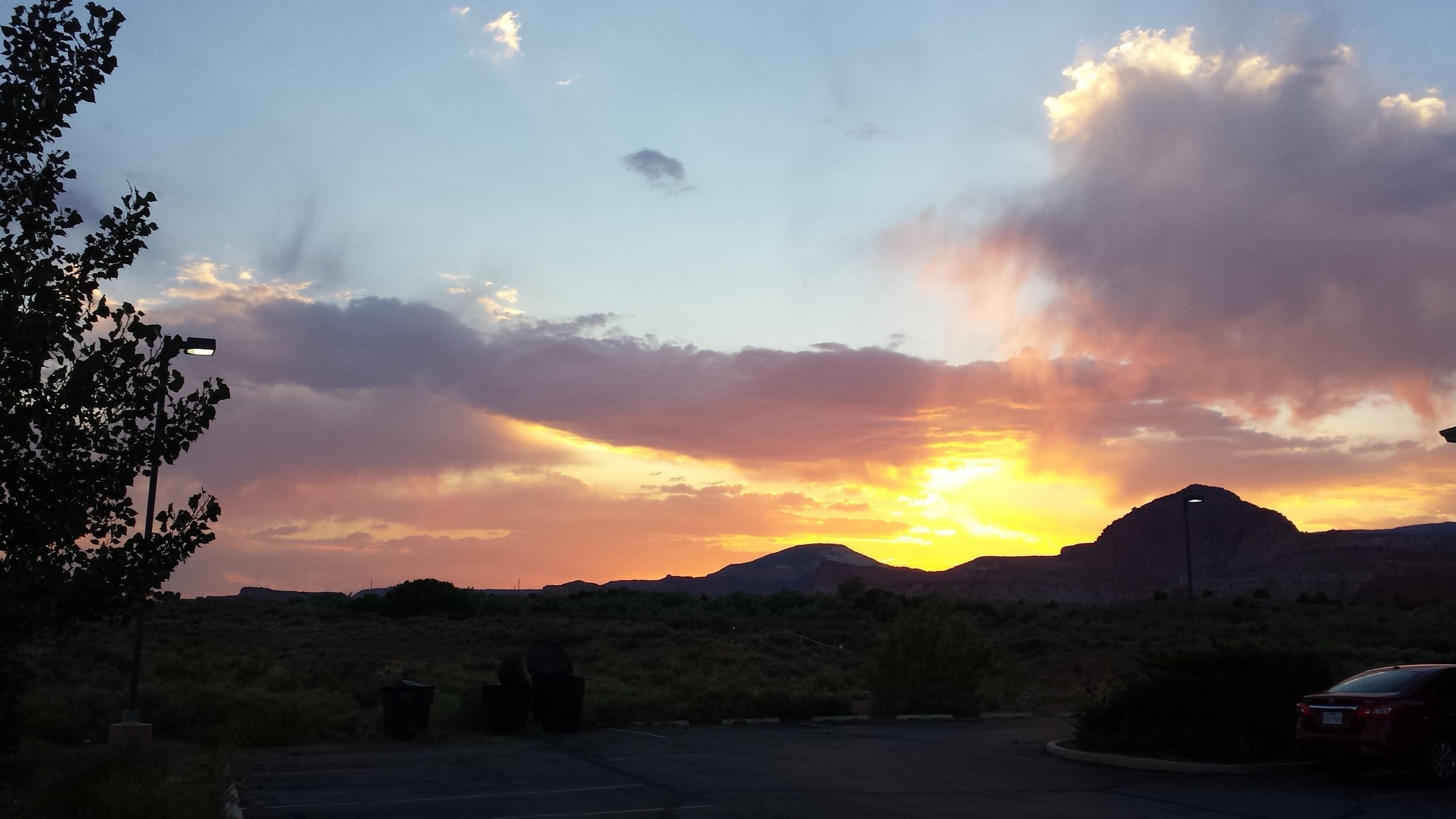 A parking lot with a mountain in the background during sunset.
