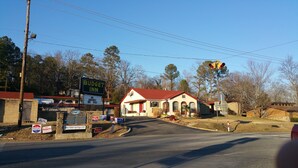 A small building with a red roof, a sign for a Budget Inn, and various political campaign signs. - Budget Inn (Heber Springs)