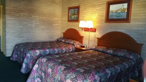 A room with two beds, a brick wall, and two framed pictures. - Budget Inn (Heber Springs)