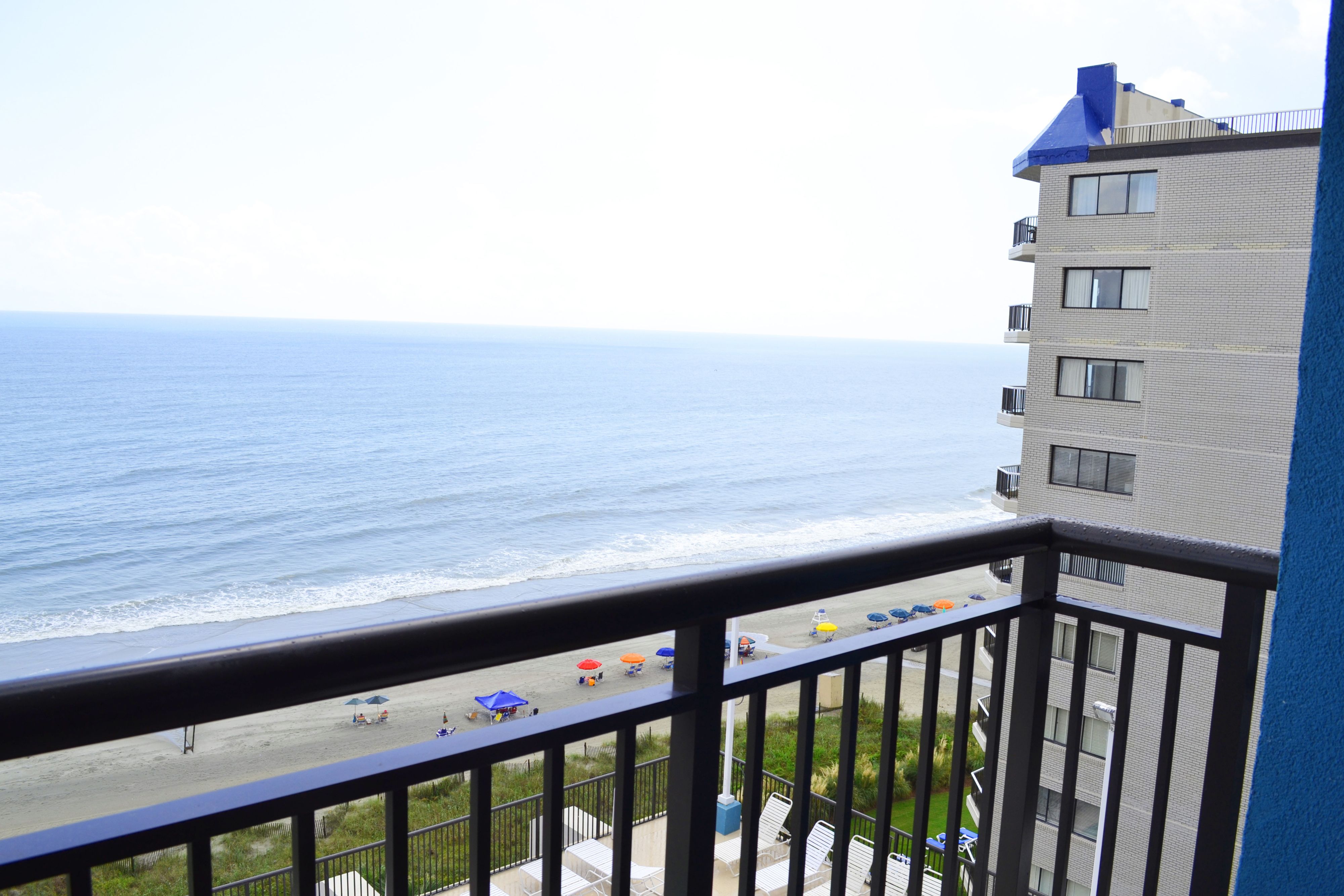 A balcony with a view of the beach and ocean.