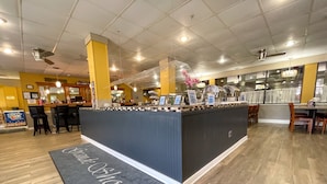 Zona de bufé con una mesa central, varias estaciones de comida y arreglos de asientos.