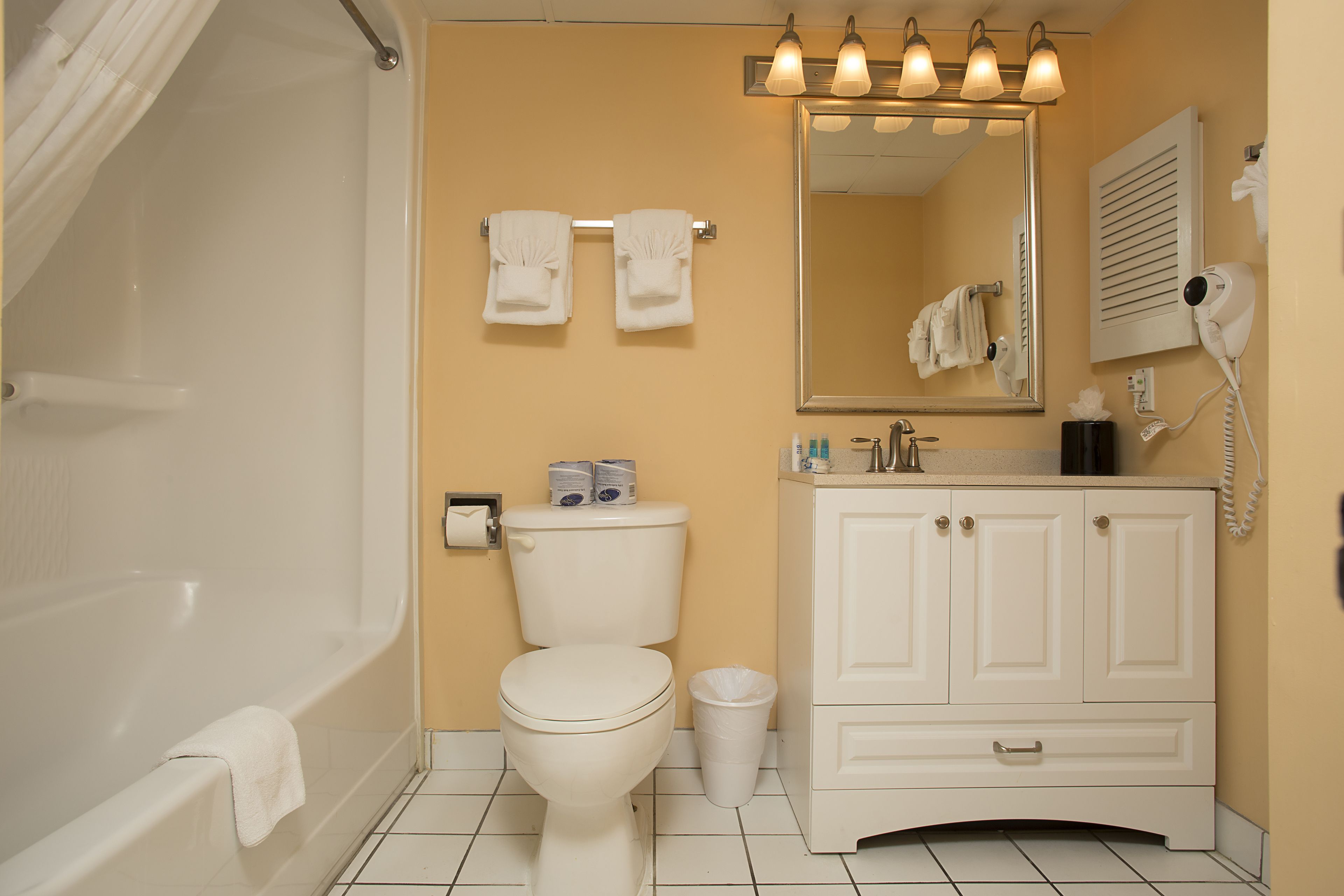 A bathroom with a bathtub, toilet, sink, and mirror.