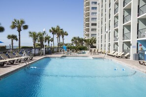 A swimming pool with lounge chairs and palm trees. - Grande Shores Ocean Resorts Condominiums (Myrtle Beach)