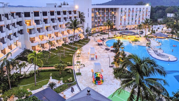 Un hotel con varias plantas, piscina y jardín ajardinado.