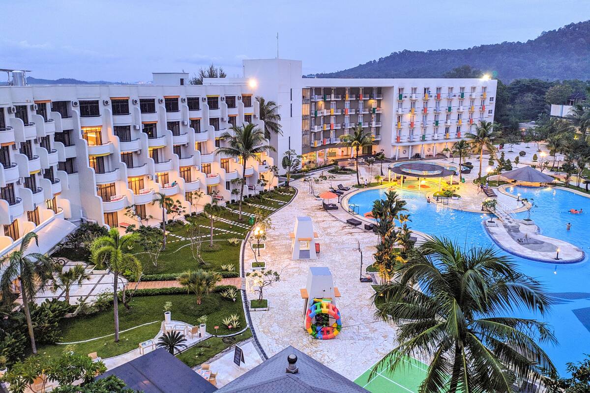 A hotel with multiple floors, a swimming pool, and a landscaped garden.