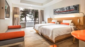 Una habitación de hotel moderna con una cama grande, un escritorio y vistas a palmeras a través de la ventana.