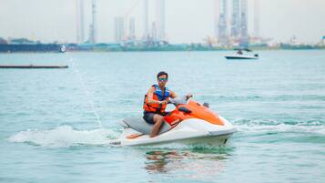 Una persona en un jet ski con un horizonte urbano de fondo.