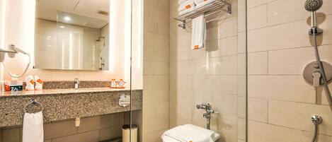 A modern bathroom with a glass shower enclosure, a toilet, and a sink with toiletries.