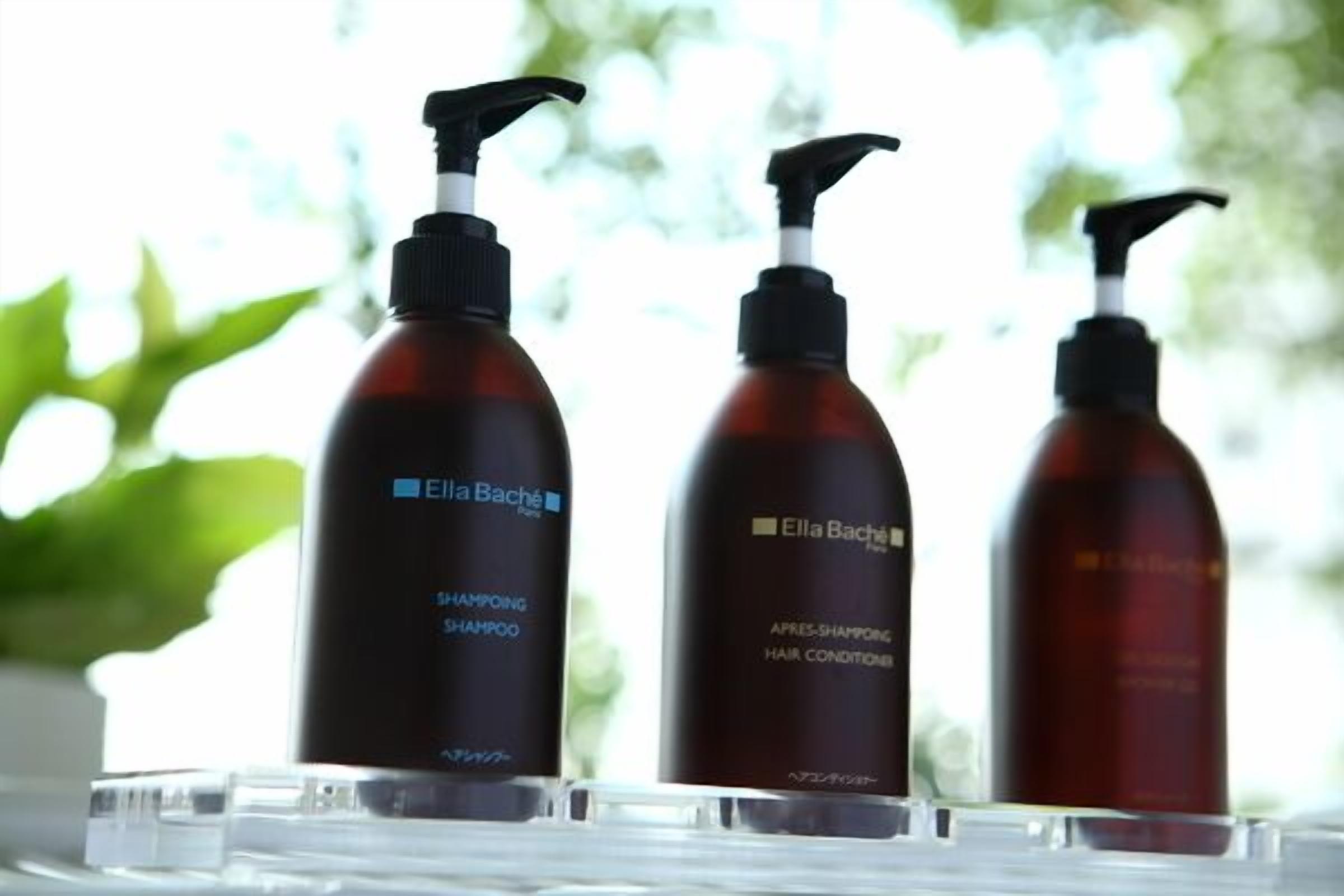 Three bottles of Ella Baché hair care products on a clear surface.