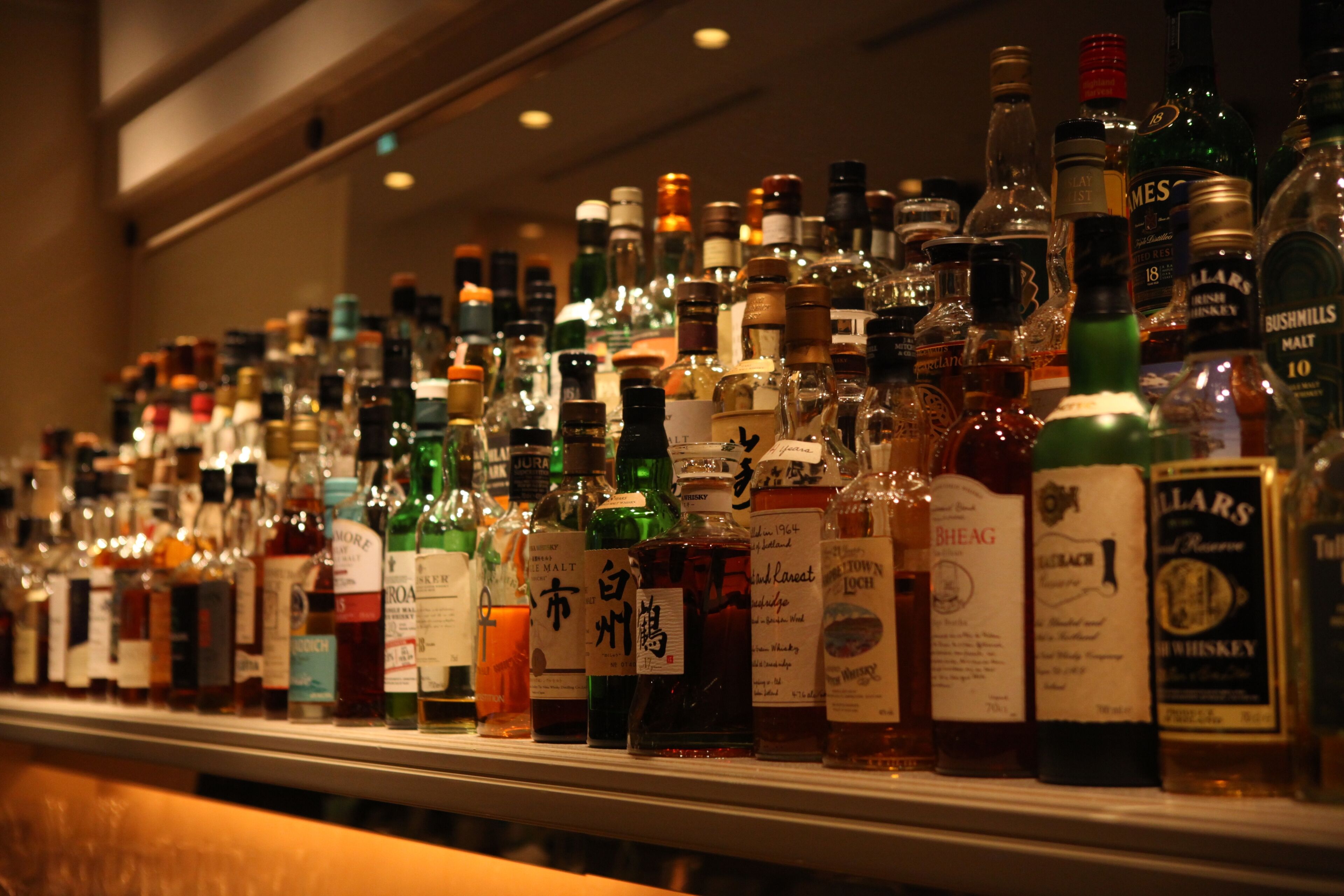 Um bar com diversas garrafas de bebidas alcoólicas expostas nas prateleiras.