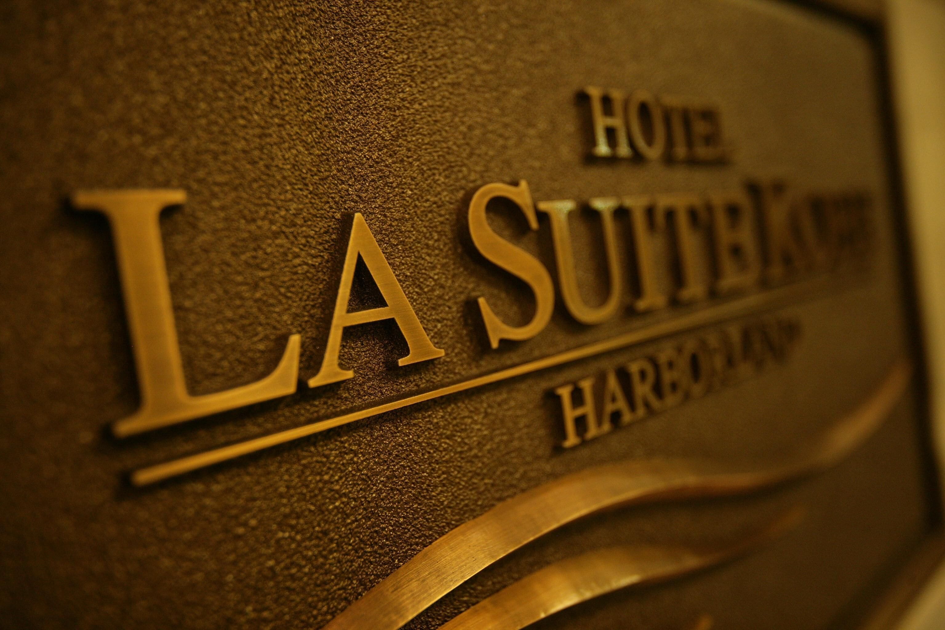 A close-up of a sign with the text "Hôtel La Suite-Kam" and "Harbor".