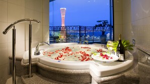 A luxurious bathroom with a large bathtub, a glass-enclosed window, a balcony with a view of a tower, and a bottle of champagne. - Hotel La Suite Kobe Harborland (Kobe)