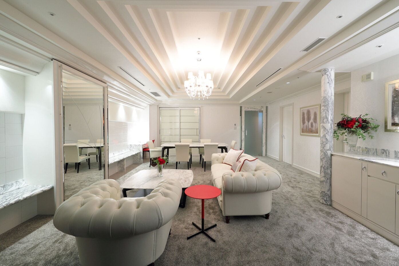 A spacious living area with a large sofa, a coffee table, and a dining table set for four.