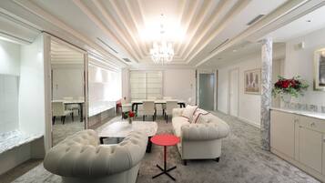 A spacious living area with a large sofa, a coffee table, and a dining table set for four.
