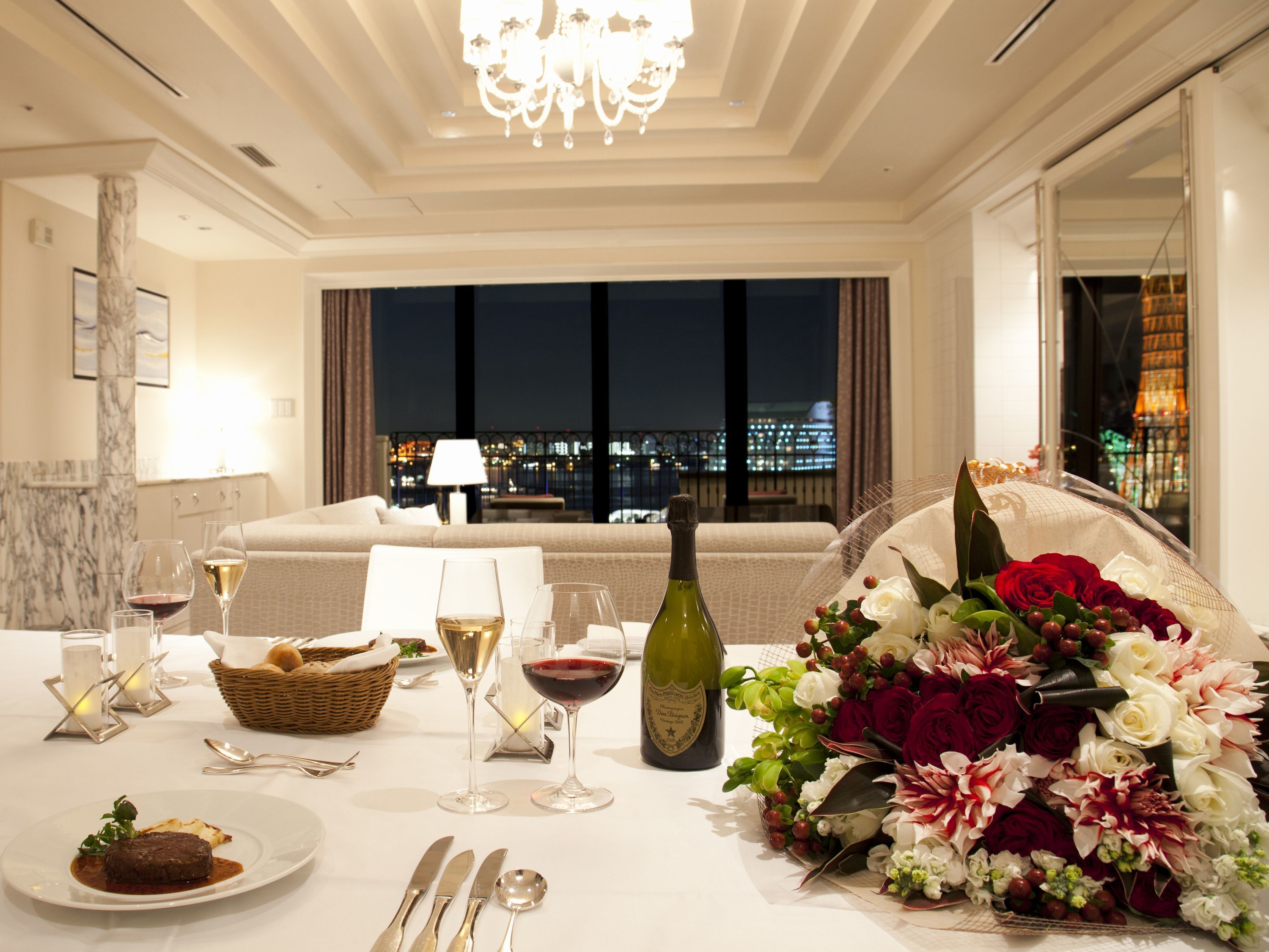 A dining table set with wine glasses, a bottle of wine, a plate of food, and a bouquet of flowers.