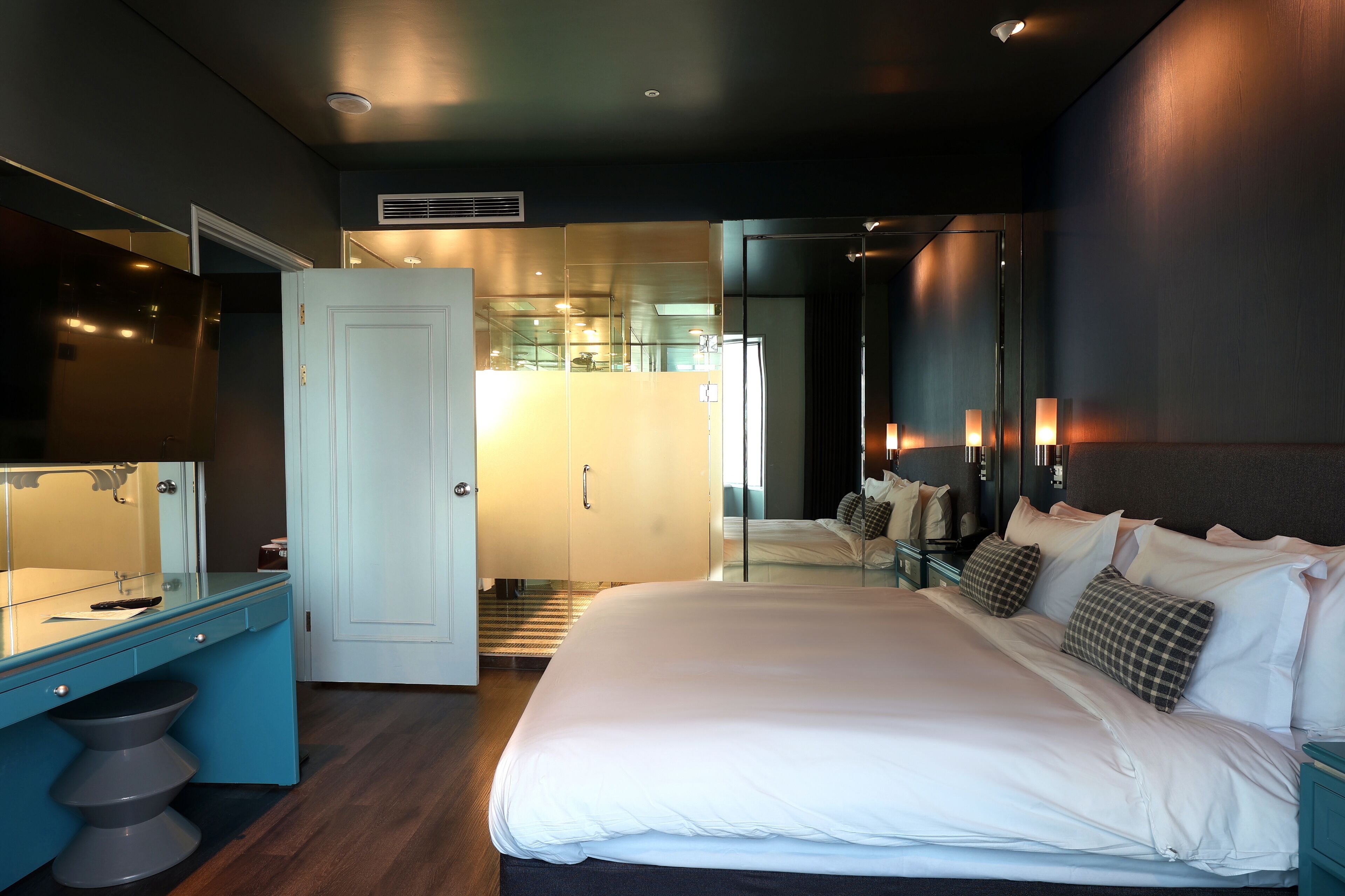 Et moderne hotelværelse med en stor seng, eget badeværelse og et skrivebord med spejl.