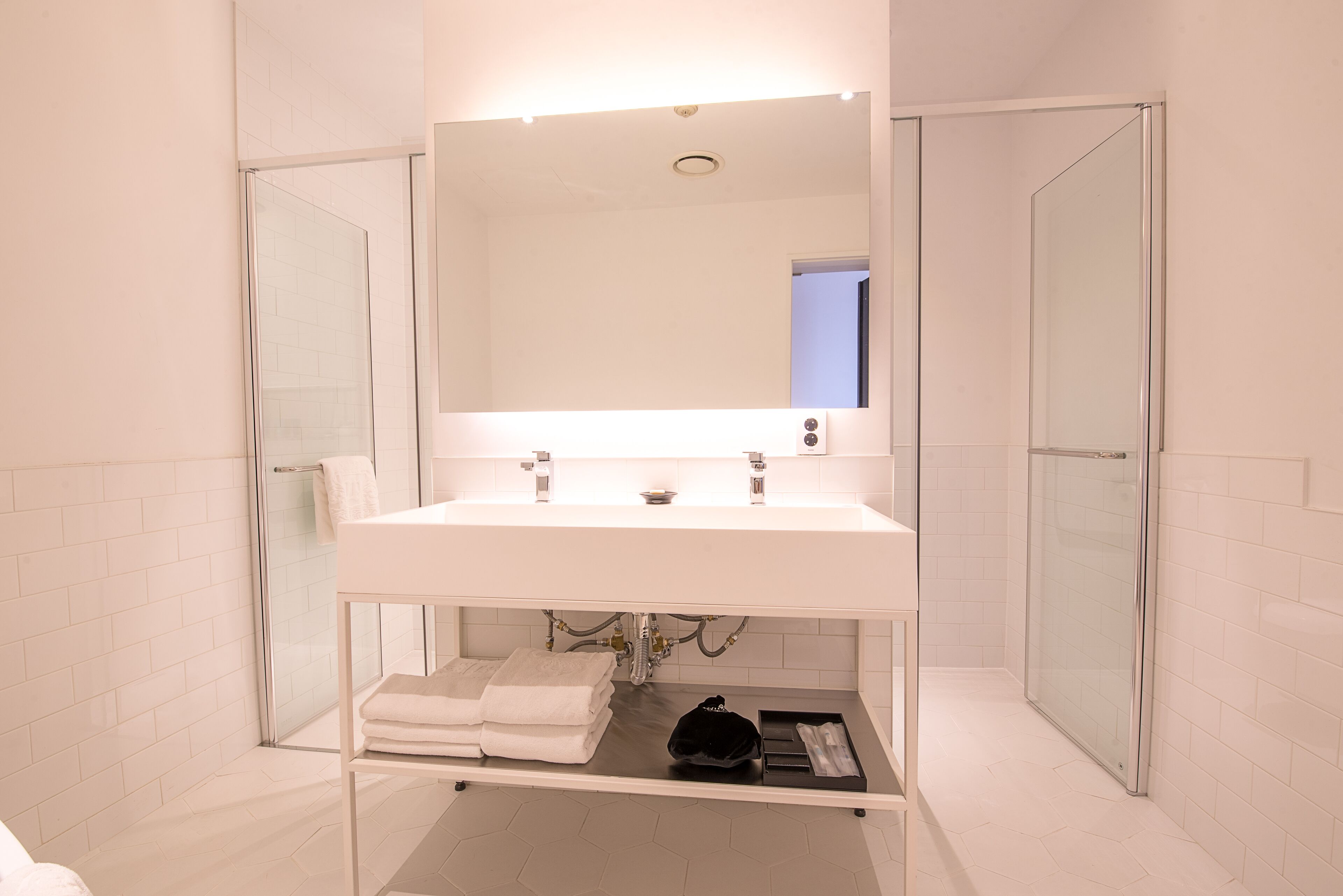 A modern bathroom with a white sink, a large mirror, and a glass shower enclosure.