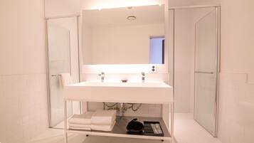 A modern bathroom with a white sink, a large mirror, and a glass shower enclosure.