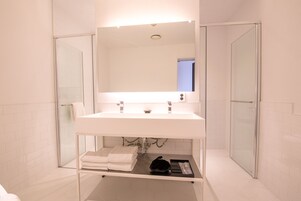 A modern bathroom with a white sink, a large mirror, and a glass shower enclosure.