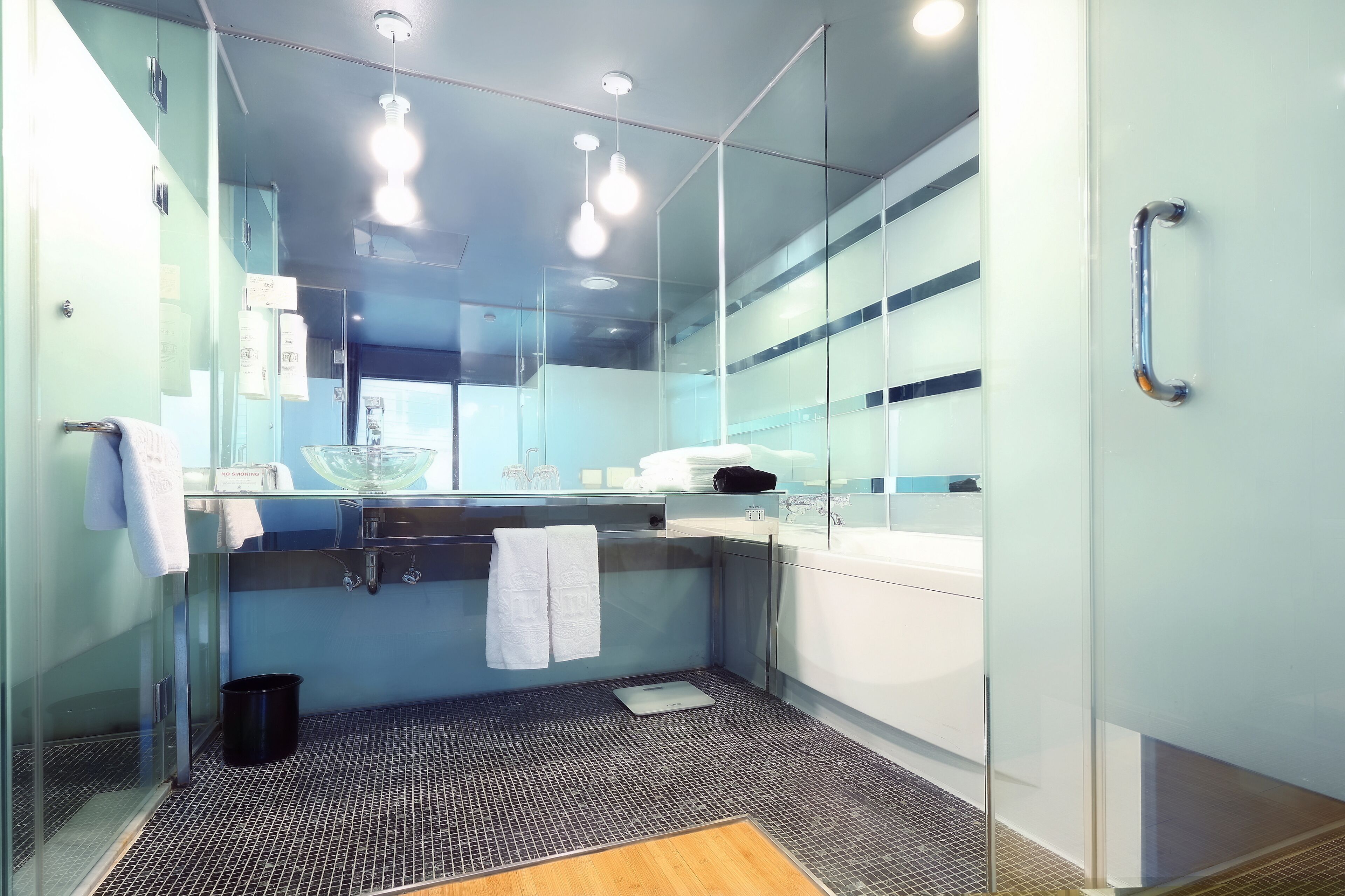 Un bany modern amb un envàs de dutxa de vidre, un lavabo blanc i una barra de tovalloles.