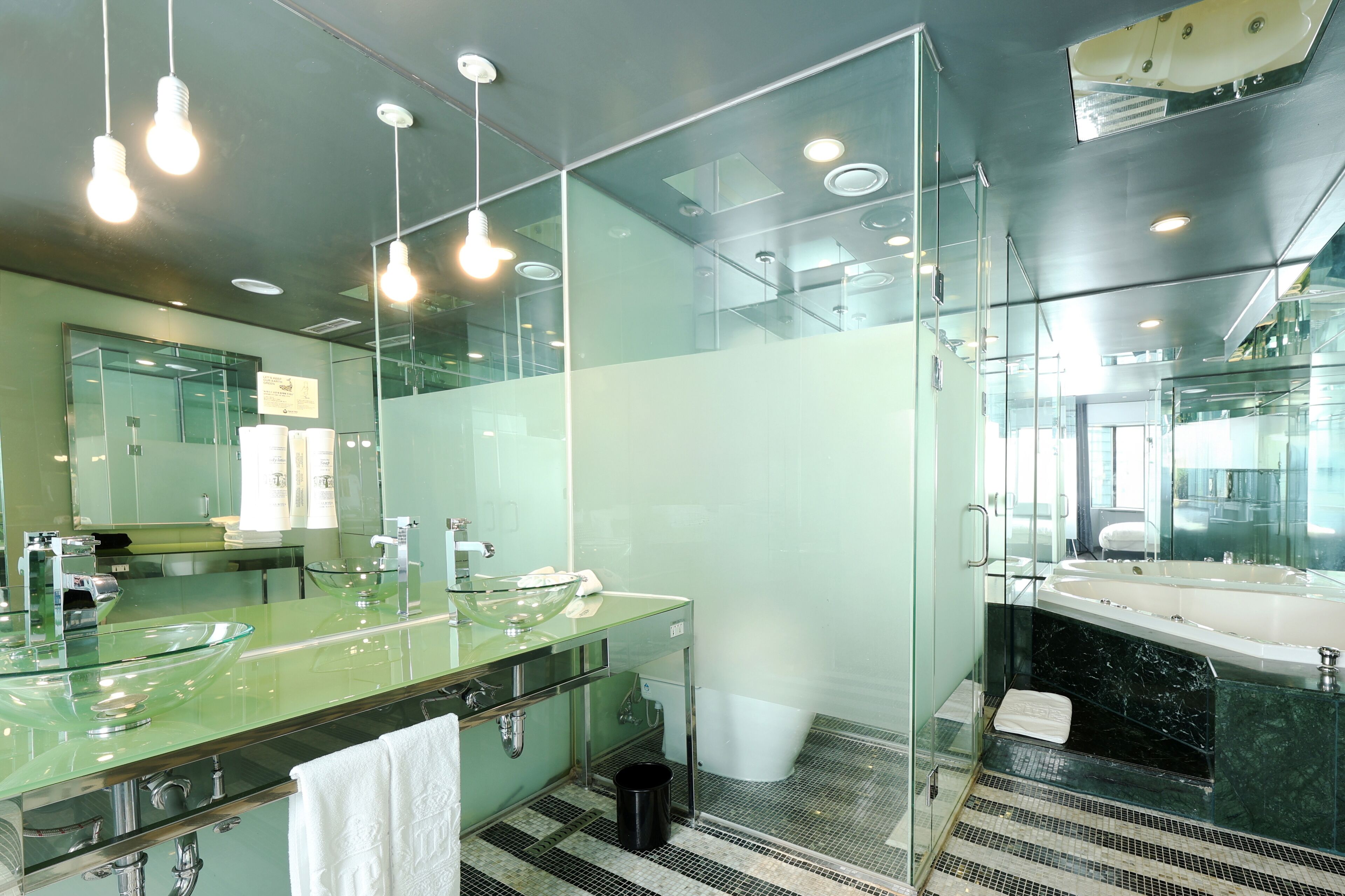Un baño moderno con ducha de vidrio, una bañera grande y un lavabo doble.