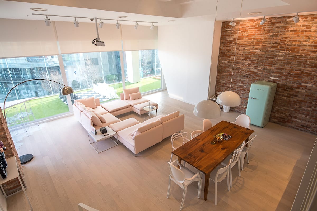 Un salon moderne avec une grande fenêtre, une table à manger en bois et un mur en briques.