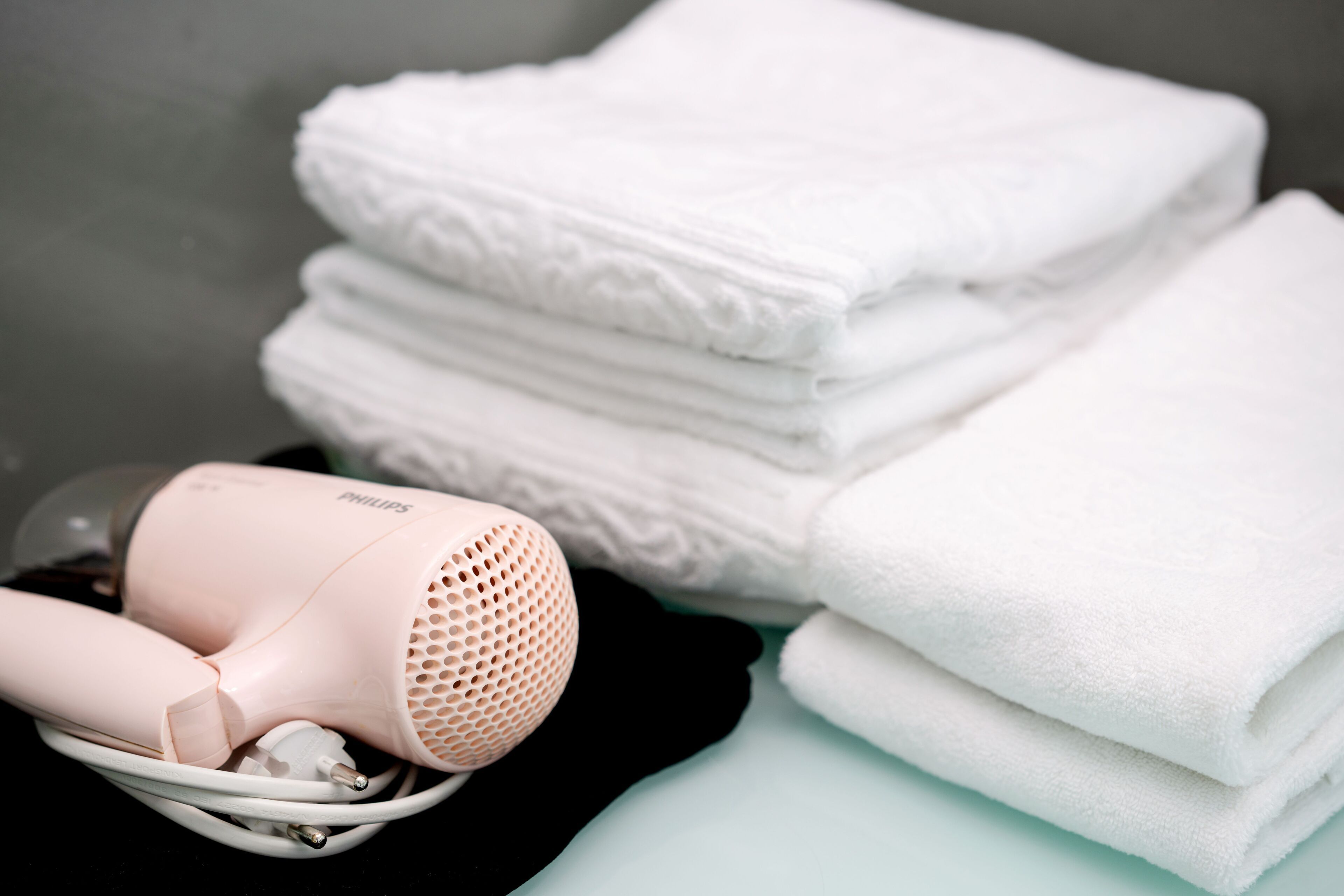 A hair dryer and folded towels on a surface.