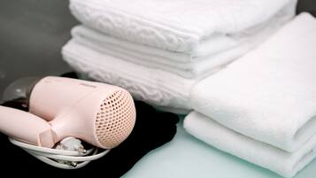 A hair dryer and folded towels on a surface.