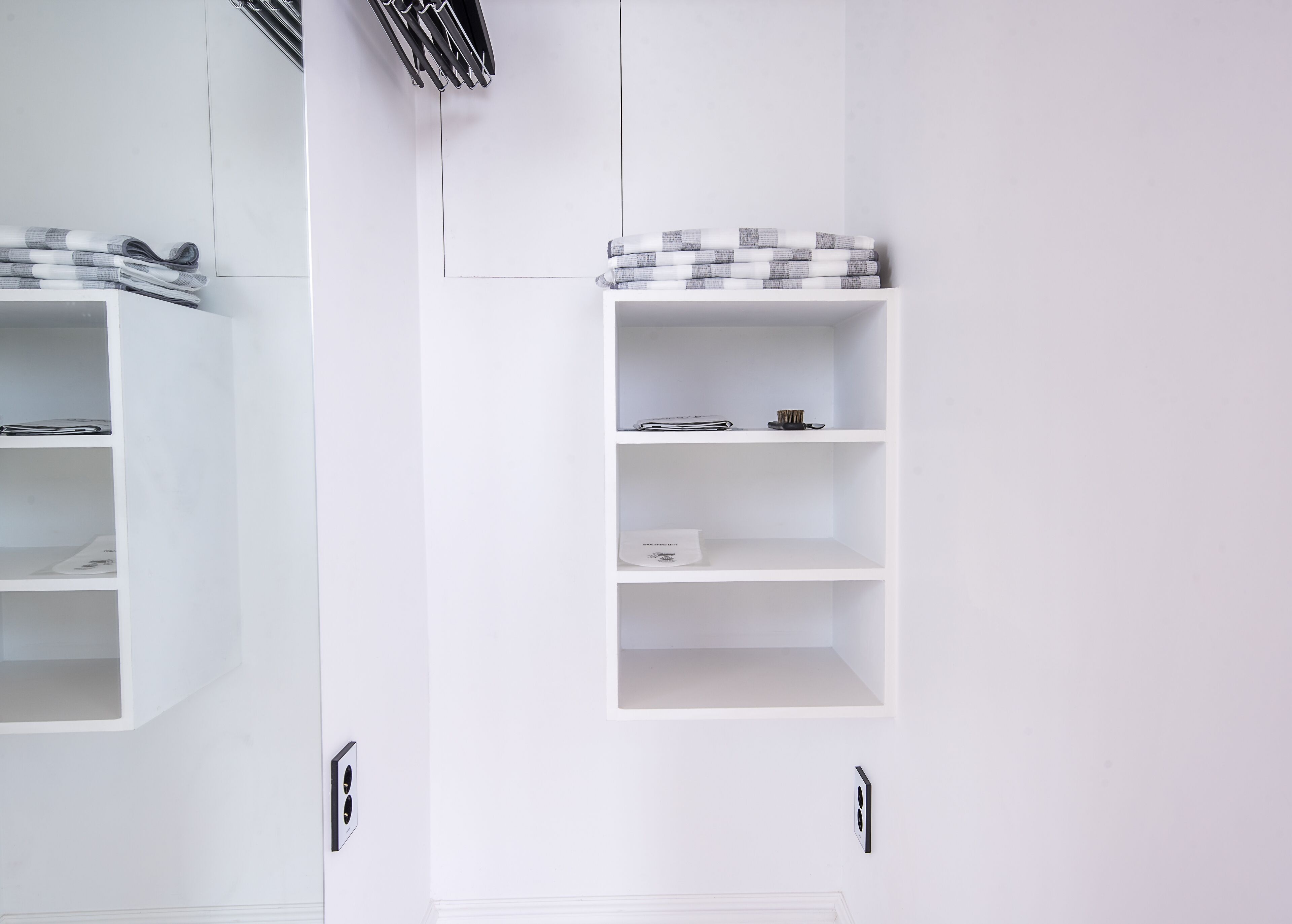 Un armario blanco con varios estantes, algunos con ropa doblada y un objeto pequeño en la repisa superior.
