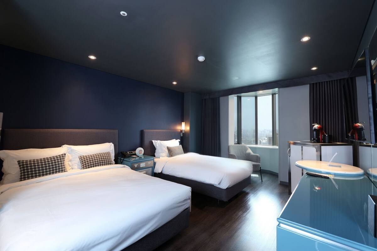 Une chambre d’hôtel moderne avec deux lits, un bureau et une chaise.