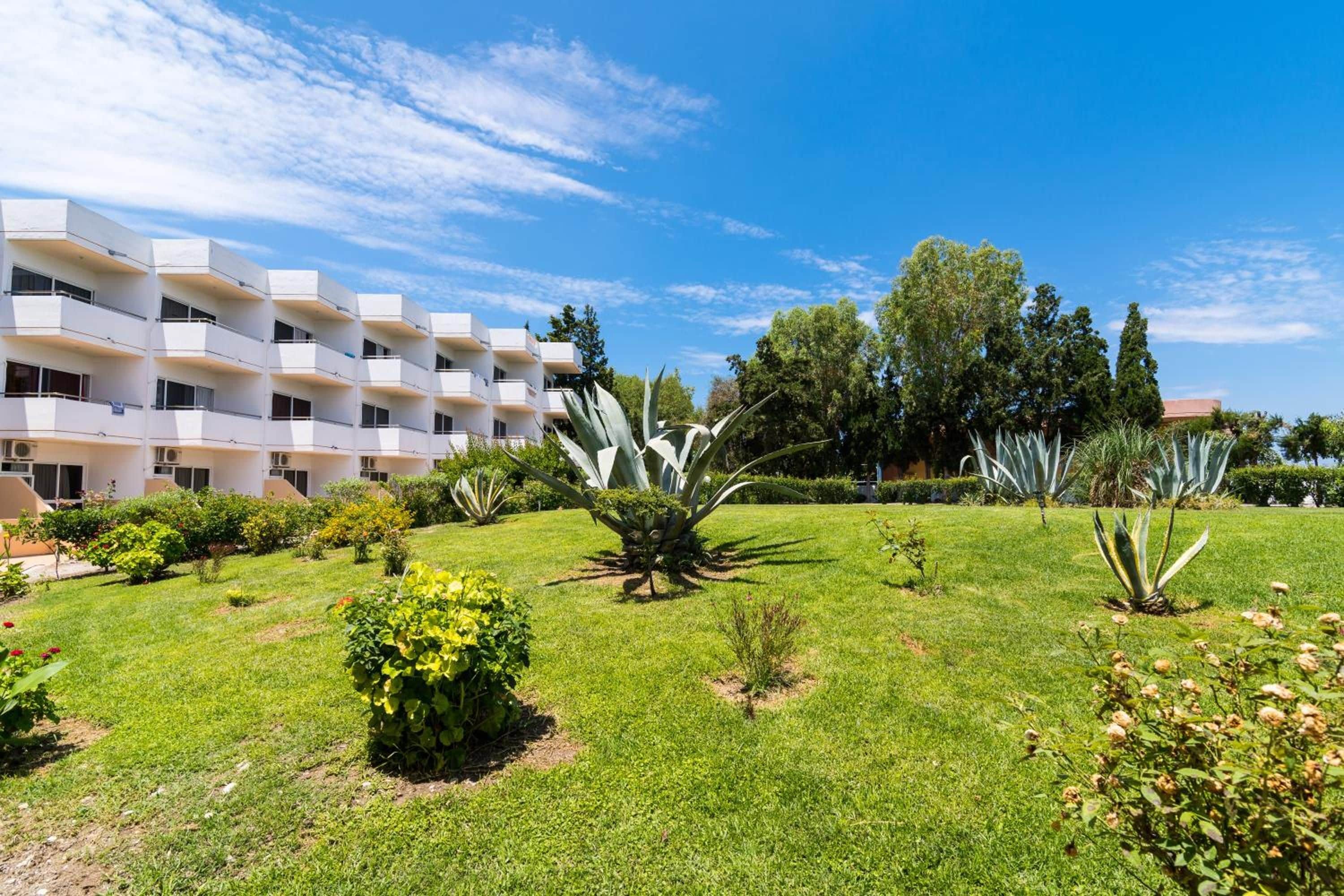 Un bâtiment moderne doté de nombreux balcons et d’un jardin bien entretenu où l’on trouve diverses espèces de plantes.
