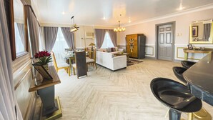 A spacious living area with a sofa, dining table, and chairs. There is a chandelier and a cabinet in the room. - Miramar Hotel (Manila)