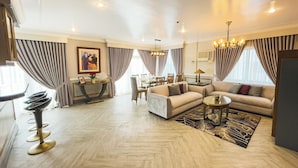 A spacious living room with a sofa set, a dining table, and a chandelier. - Miramar Hotel (Manila)
